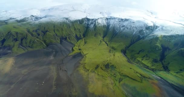 アイスランドの山々の美しい滝の空中ショット 川は山の頂上からその底まで水を運んでいる 山は緑の春草の層で覆われている — ストック動画