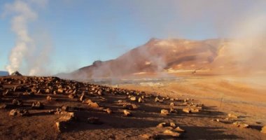 Güneşli bir günde, İzlanda 'daki Hver sülfürik içicisinde pek çok fümerolün düzenli bir çekimi. Sağ tarafta, onlardan yükselen hafif sülfürik dumanlı küçük çamur lekeleri görüyoruz. Sol tarafta yoğun beyaz duman tüten fümeroller var..