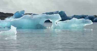 İzlanda 'daki panoramik manzara dağlık arazi ve eteklerdeki göl. Panoramik manzara canlı yeşil tepeler ve tepeler gösteriyor, ve tepeden akan muhteşem suyla küçük bir şelale ve dağ eteklerindeki güzel bir göle dökülüyor..