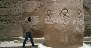 Seyirci tarafından keşfedilen antik firavun sütunları arasında gezinen bir turisti filme çeken hareketli bir kamera, kıvrımlar eski hizmetçiler ve insan yüzleri şeklinde, sütunlar da büyük duvarlarla çevrili.