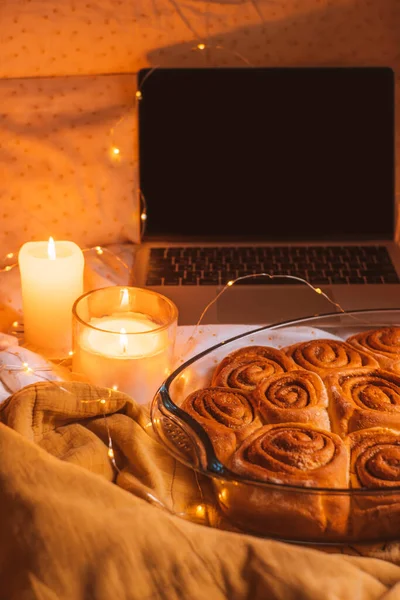 Tarçın ruloları, dizüstü bilgisayarı, mumları, ışıkları ve Noel çanları olan rahat bir Noel yatağı..
