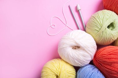 Pembeye izole edilmiş kalp sembolü olan çok renkli örgü ipliği topları..