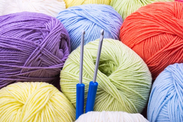 2つのかぎ針編みのフックと編み物糸の多色のボールのクローズアップ背景 — ストック写真