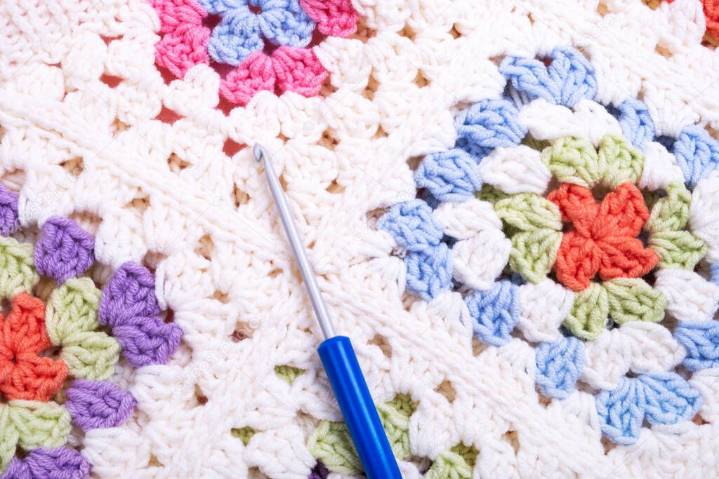 Closeup background of multicolored crochet knitting and hook.