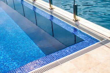 Parlak mavi sonsuzluk yüzme havuzu, deniz ve dağ manzaralı bir otel..