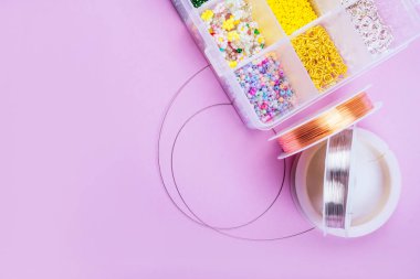 Pembe arka planda mücevher ve tel dizisi yapmak için araçları olan farklı inci boncuklardan oluşan yaratıcı düz tabaka.