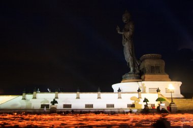 Buda heykeli etrafında elinde yanan mumlar
