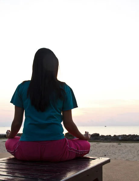 Donna che medita sulla spiaggia al tramonto. — Foto Stock