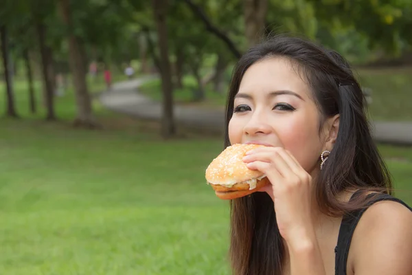 Chica comiendo una hamburguesa con queso — Foto de Stock