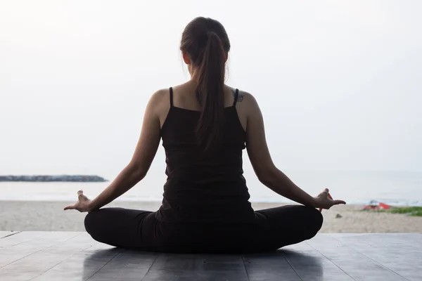 Frau praktiziert morgens Yoga auf friedlichem Meer — Stockfoto