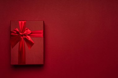 Kırmızı kurdeleli kırmızı hediye kutusu kırmızı arka plan minimalizmi