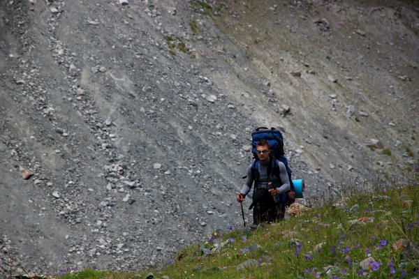 Un homme avec un sac à dos sur la piste dans les montagnes — Photo