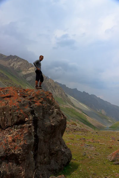 Ένας άνθρωπος στέκεται πάνω σε ένα βράχο. στο πλαίσιο των βουνών και — Φωτογραφία Αρχείου