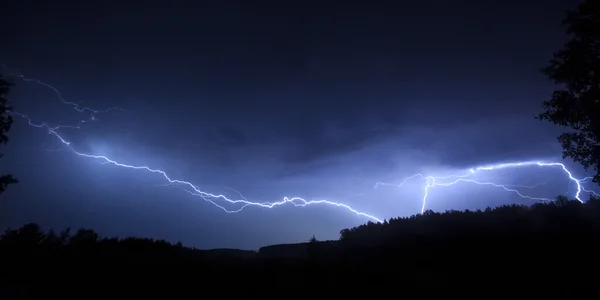 Lightning in sky on the background of trees — Stock Photo, Image