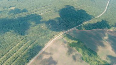 Rusya, Ural. Orman üzerinde uçuş, tarla yolu. Bulutlardan gölgeler, Hava Görünümü  