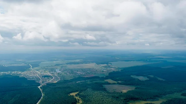 Russia, Ural. Flight over woodland, fields road. Shadows from the clouds. Flying through the clouds, Aerial View