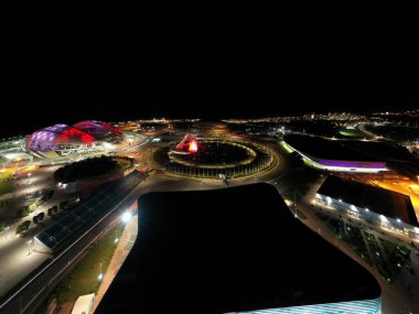 Sochi, Rusya - 5 Eylül 2021: Sochi Olimpiyat Parkı 'nın havacılık panoraması. Olimpik Alev Kasesi, Şarkı Söyleyen Çeşme. Bir gösteri var. Arena Fisht. Çok renkli bir aydınlatma. Gece