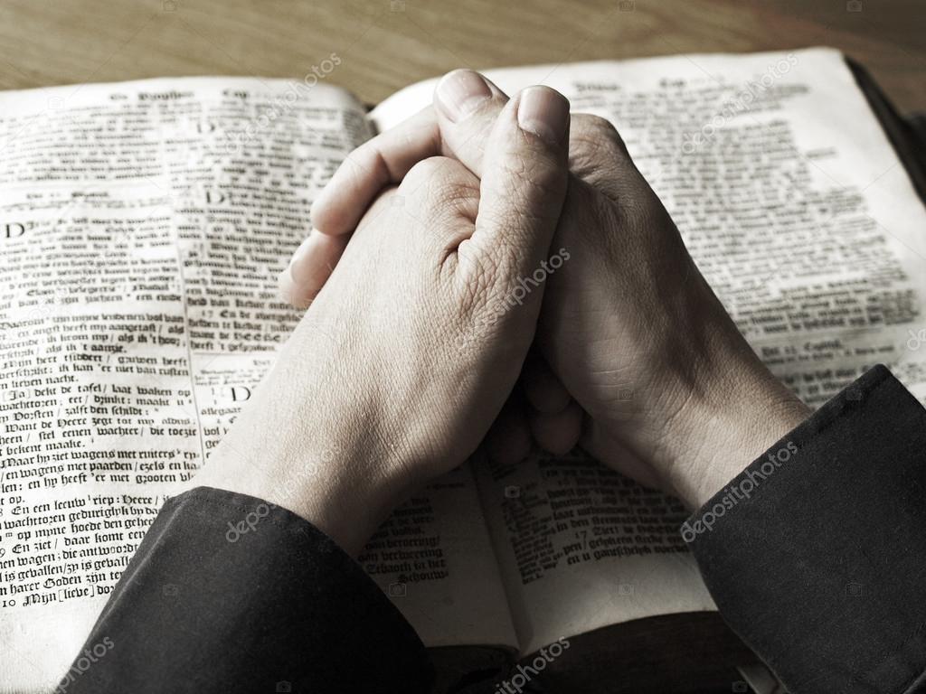 Hands praying on bible