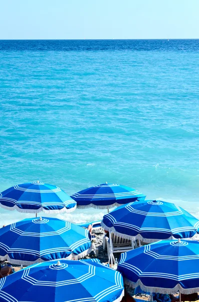 Concept of holiday blue beach with parasols in Nice