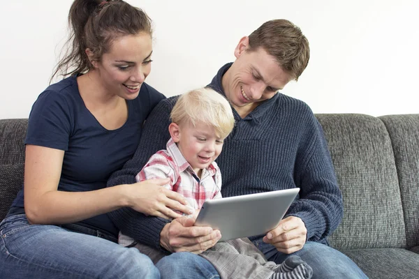 Familia feliz en el sofá con la tableta PC — Foto de Stock