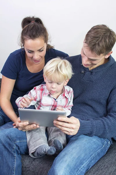 Familia feliz en el sofá con la tableta PC — Foto de Stock