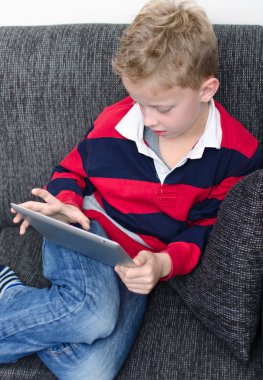 kanepede ipad ile oynayan çocuk