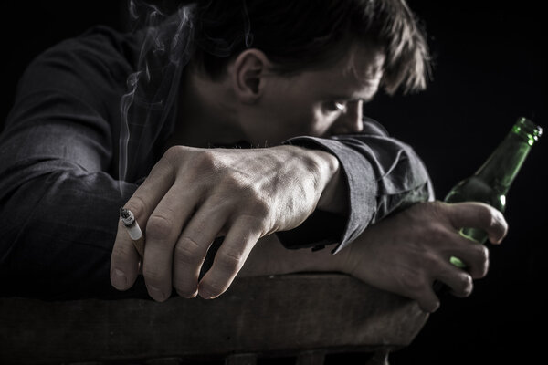 Depressed man smoking and drinking beer