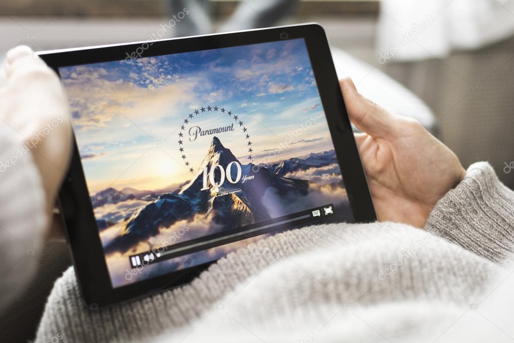 Man watching paramount pictures movie on tablet pc at home. Relaxing in chair.