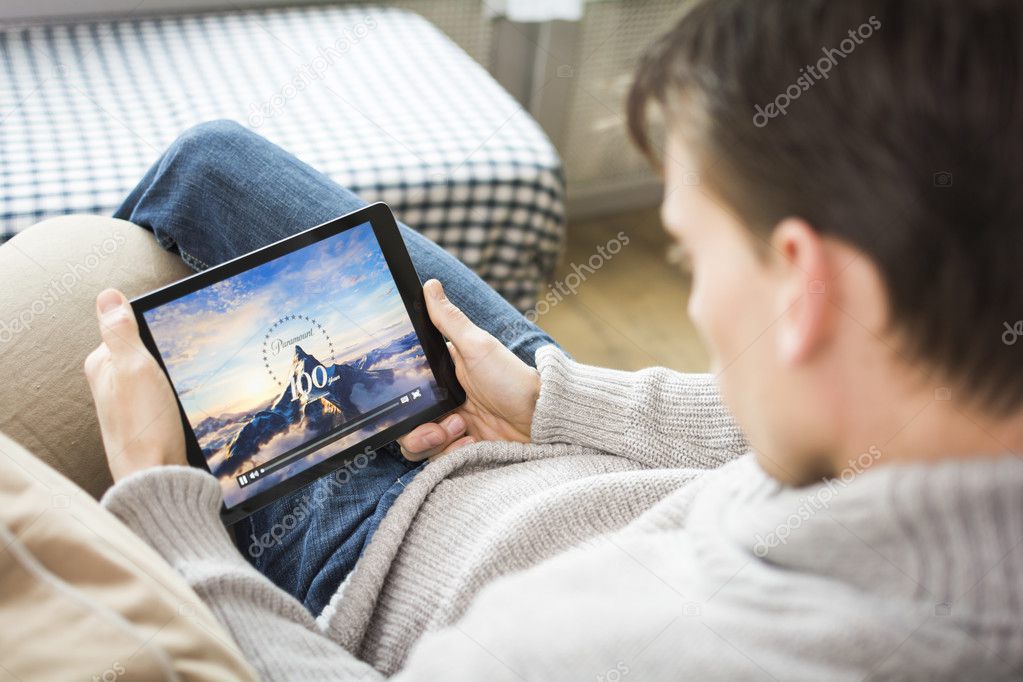 Man watching paramount pictures movie on tablet pc at home. Relaxing in chair.