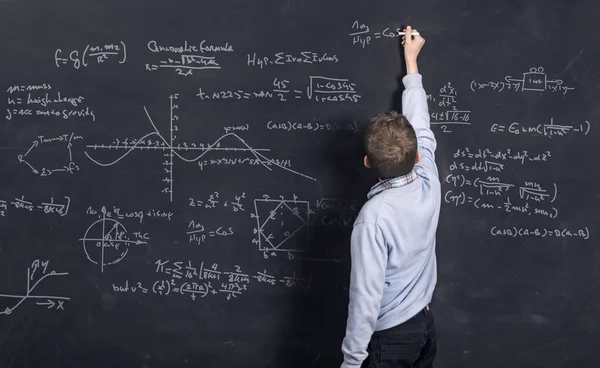 Niño inteligente haciendo matemática en pizarra —  Fotos de Stock