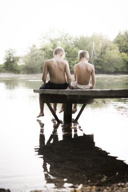 Two boy playing at the lake clipart