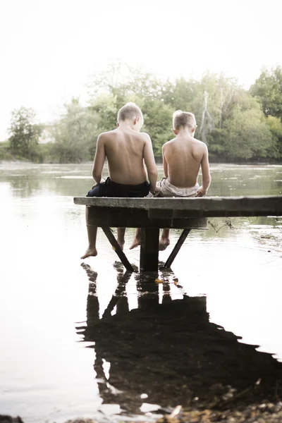 两个男孩坐在码头上 — 图库照片