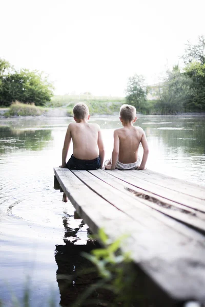 Twee jongens zitten op een pier — Stockfoto