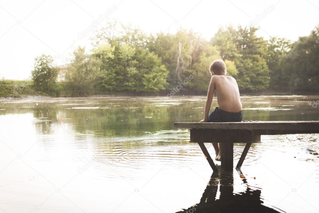 Lonely boy sitting at the lake