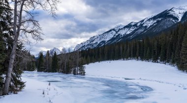 Kışın Donmuş Bow River, arka planda Kanada Kayalıkları. Banff Ulusal Parkı 'ndaki güzel manzara, Alberta, Kanada.