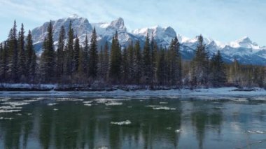 Canadian Rockies beautiful scenery in early winter. Drift ice floating on Bow River, snow capped Mount Rundle mountain range reflections. Canmore, Alberta, Canada.