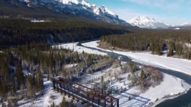 Aerial panorama view of Bow River valley forest in winter. Snowcapped Canadian Rockies mountain range beautiful scenery. Canmore Engine Bridge. Alberta, Canada.
