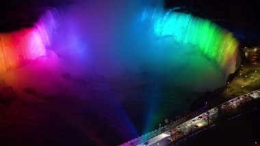 Horseshoe Şelalesi 'nin alacakaranlık saatindeki kış aydınlatmasının havadan görüntüsü. Niagara Şelalesi şehir merkezi ufku. Göz kamaştırıcı manzara alacakaranlıktan geceye.