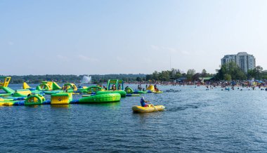 Barrie, Ontario, Kanada - 25 Temmuz 2021: İnsanlar yaz mevsiminde Centennial Park Plajı 'nda boş zaman aktiviteleri yapıyorlar. Kempenfelt Körfezi, Simcoe Gölü. Barrie Rıhtım Festivali. Su parklarına su sıçratma.