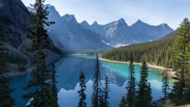 Moraine Gölü. Güneşli yaz sabahında güzel bir manzara. Gölge turkuaz mavi suda yansıyarak hareket eder. Kanada Kayalıkları. Banff Ulusal Parkı. Alberta, Kanada. 4K Zaman Hızı Uzaklaştır.