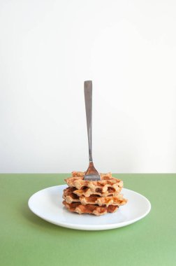 Ev yapımı Belçika waffleları, ortasında çatal olan yeşil renkli bir masa..