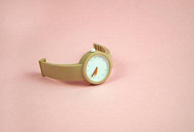 Pastel pembe arka planda bej renkli kol saati.