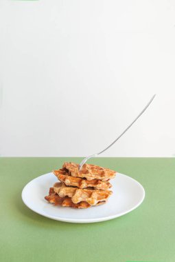 Ev yapımı Belçika waffleları, ortasında çatal olan yeşil renkli bir masa..