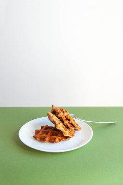 Yeşil bir masada beyaz tabakta Belçika waffle 'ı..