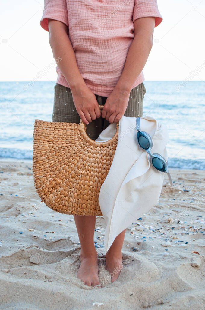 A young girl carrying straw bag to the beach in summer.
