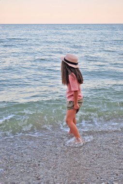 A happy smiling girl in a hat at the beach during summer vacation.