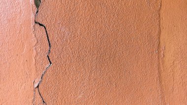 Eski turuncu duvarda çatlaklar ve soyulmuş boyalar..