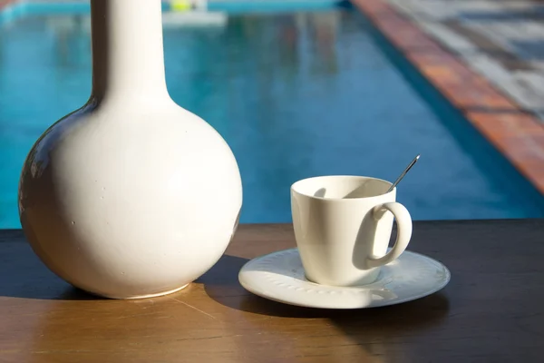 Csésze kávé egy fa asztal háttér medence — Stock Fotó