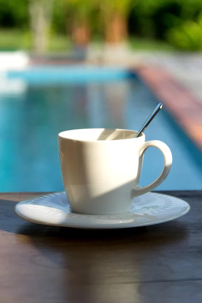 Kopp kaffe på ett träbord bakgrund simbassäng — Stockfoto