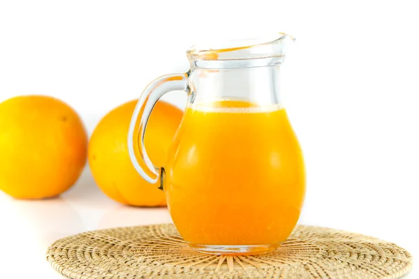 Succo d'arancia in brocca e arancia su fondo bianco — Foto Stock